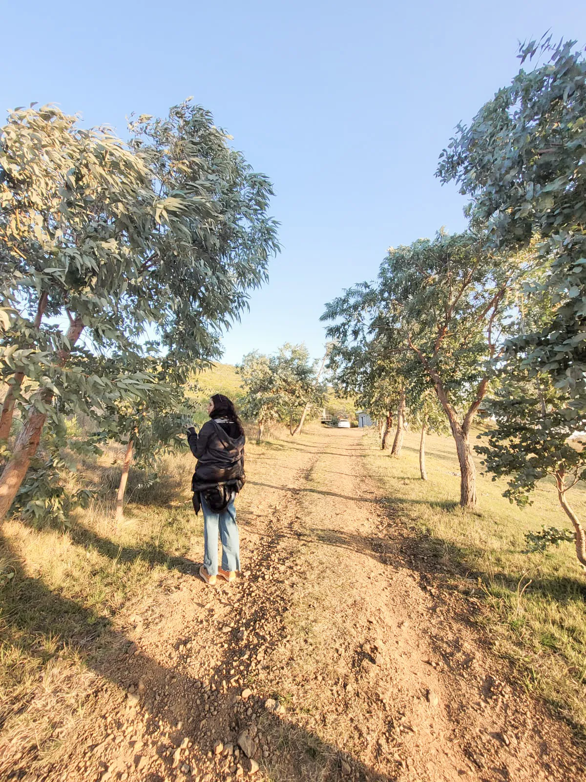 Una mujer y su hija pequeña sentadas en la arena de espaldas, mirando hacia el agua bajo un cielo nublado